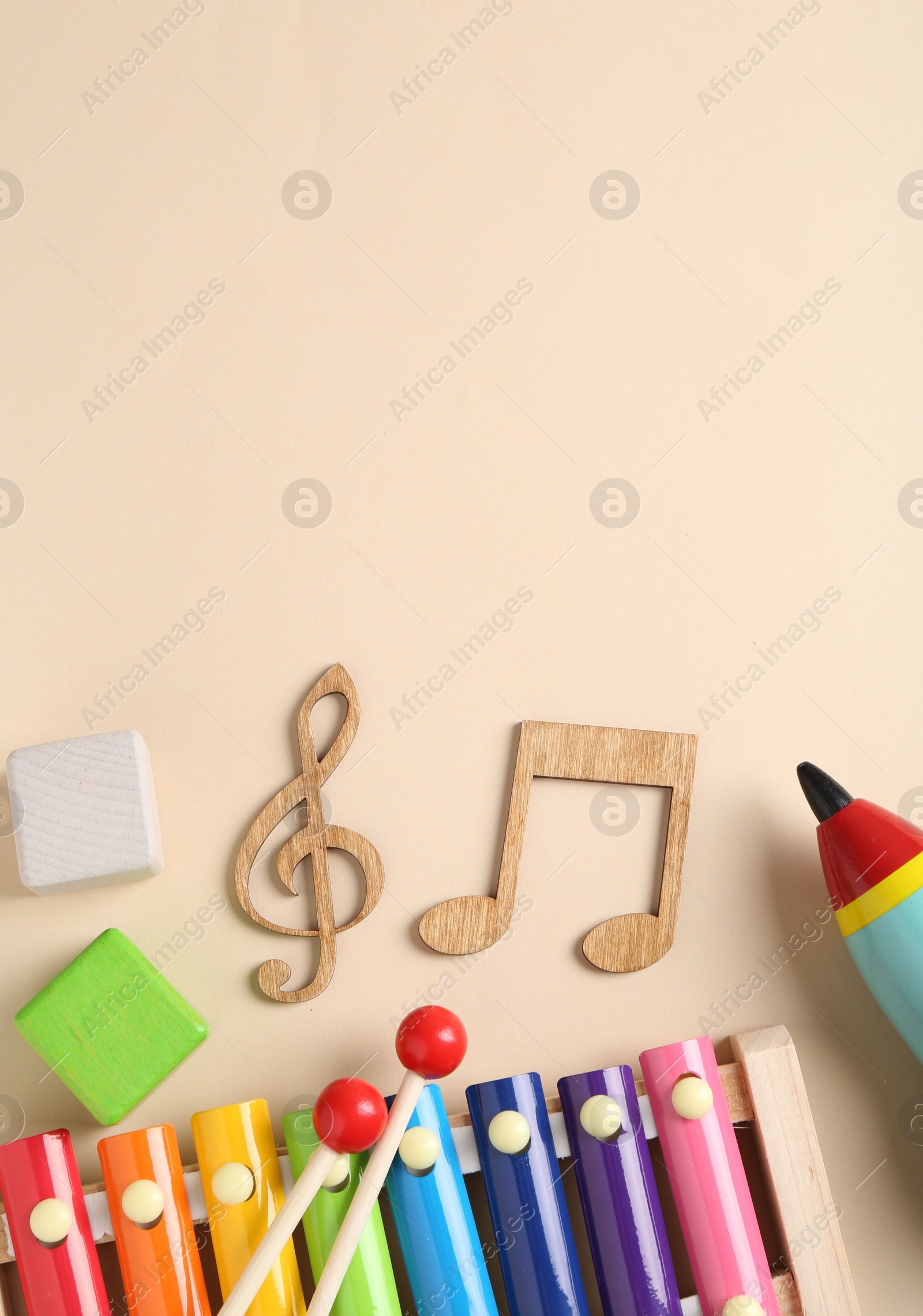 Photo of Baby song concept. Wooden notes, kids xylophone and toys on beige background, flat lay. Space for text