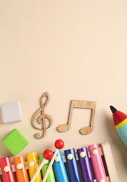Baby song concept. Wooden notes, kids xylophone and toys on beige background, flat lay. Space for text