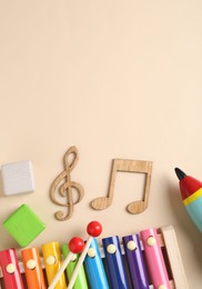 Photo of Baby song concept. Wooden notes, kids xylophone and toys on beige background, flat lay. Space for text