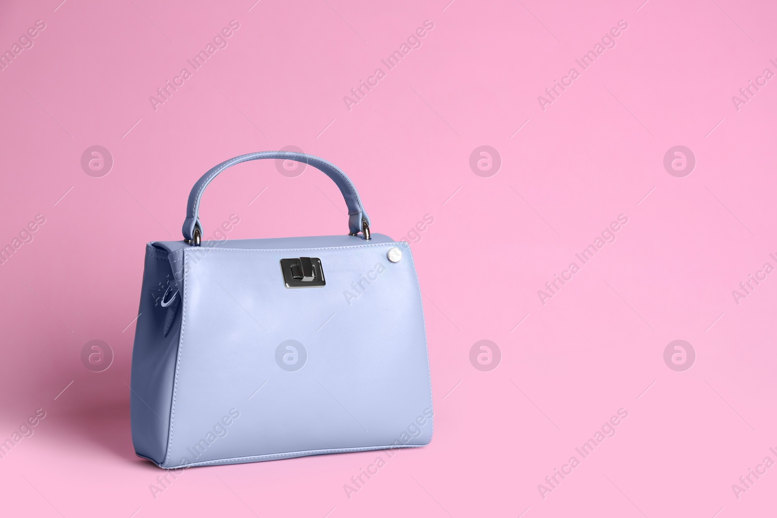 Photo of Stylish woman's bag on light pink background. Space for text