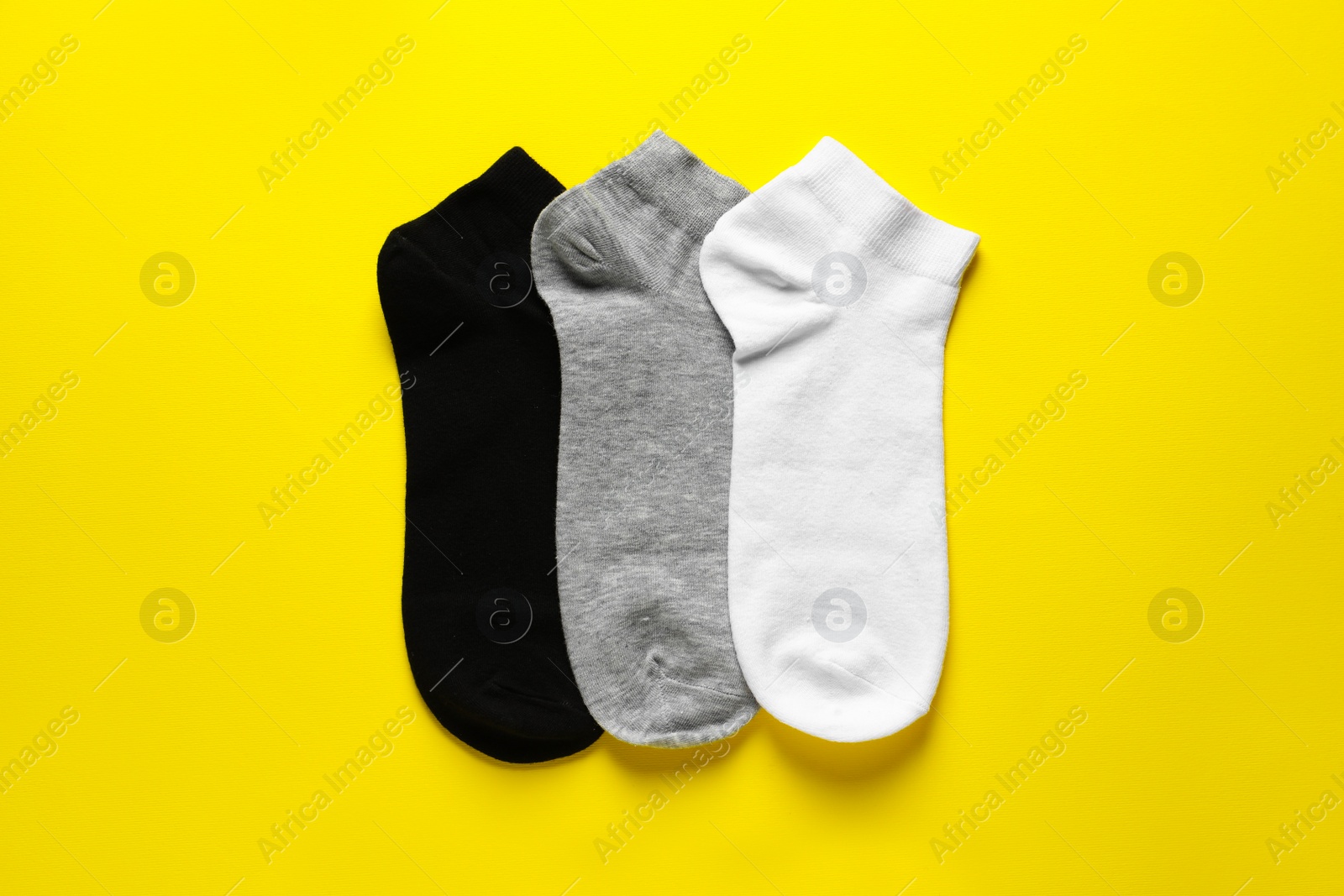 Photo of Different socks on yellow background, flat lay