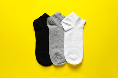 Different socks on yellow background, flat lay