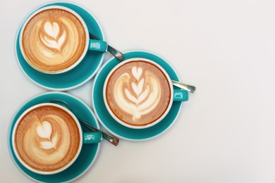 Photo of Cups of aromatic coffee on beige background, flat lay. Space for text