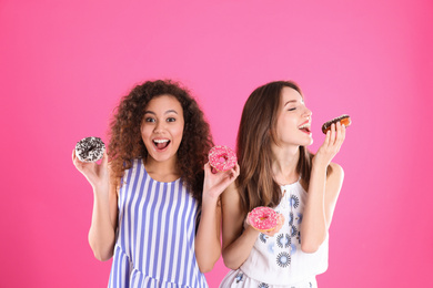 Beautiful young women with donuts on pink background