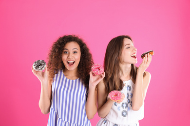 Photo of Beautiful young women with donuts on pink background