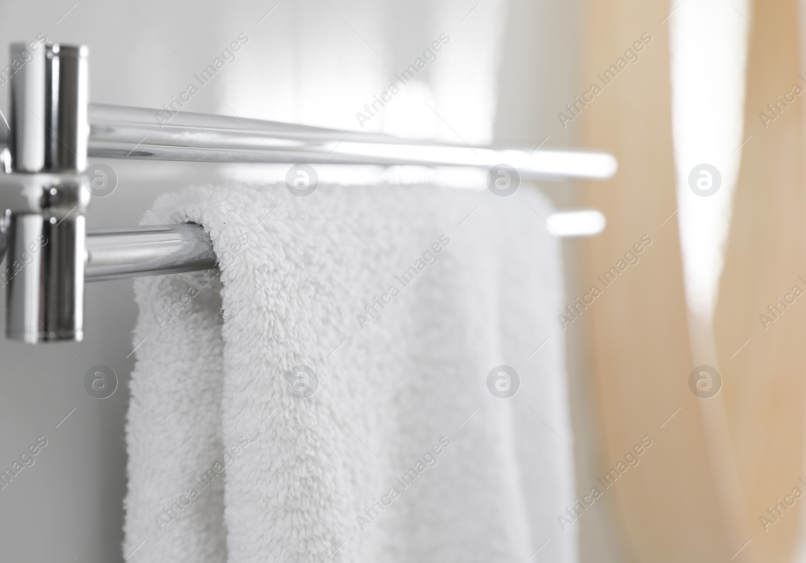 Photo of Holder with clean towel on light wall in bathroom, closeup