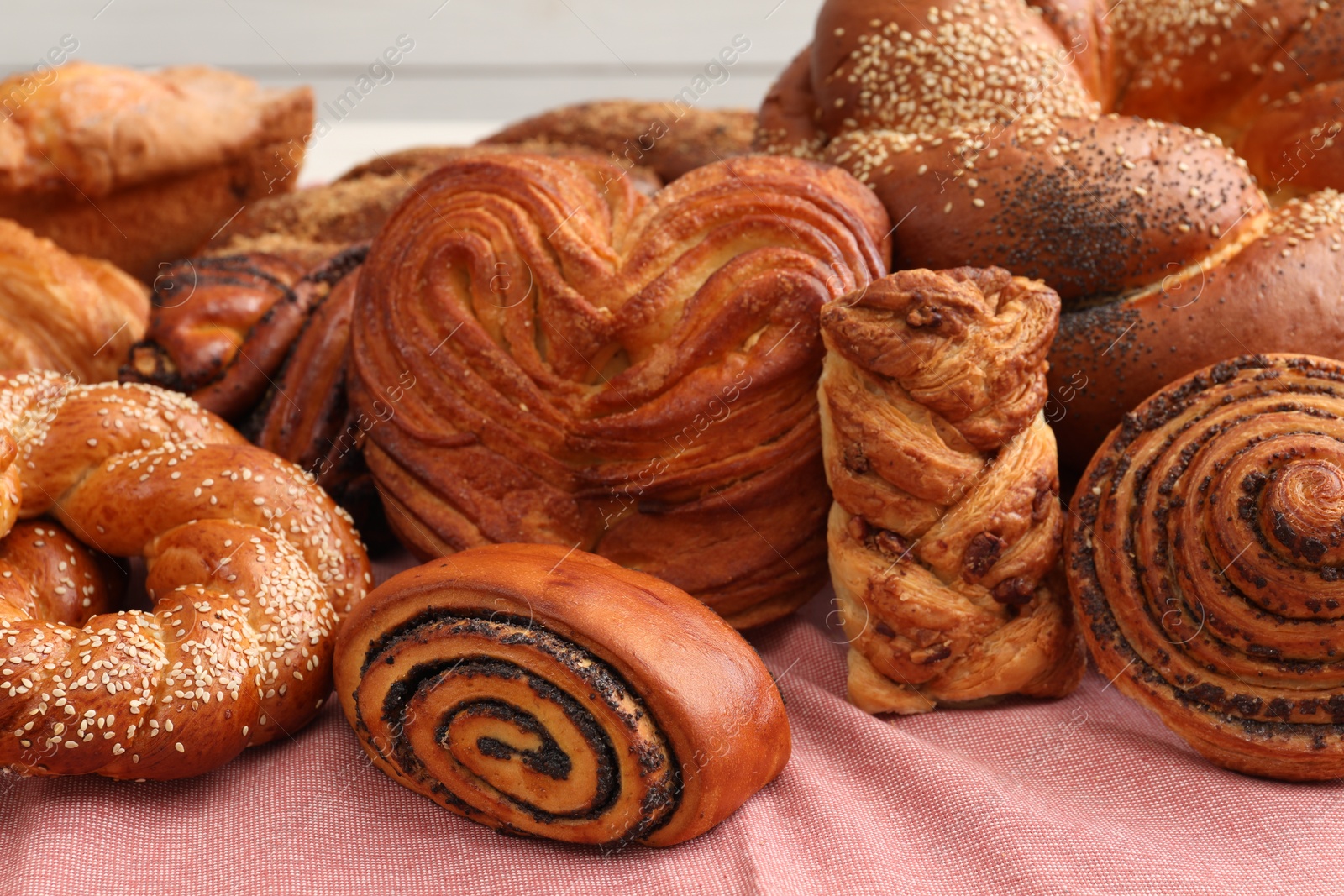 Photo of Different tasty freshly baked pastries on pink tablecloth