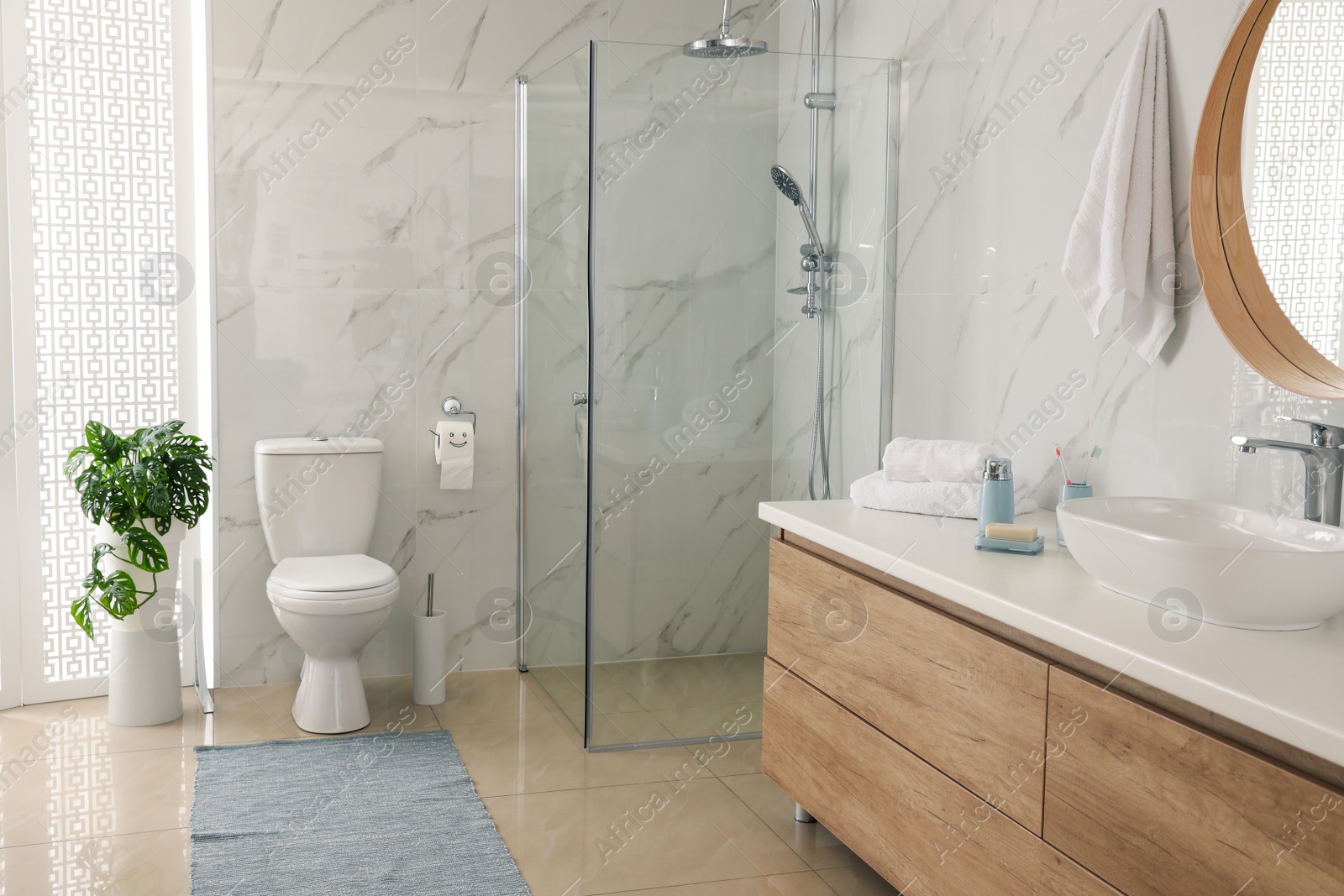 Photo of Toilet bowl near shower stall in modern bathroom