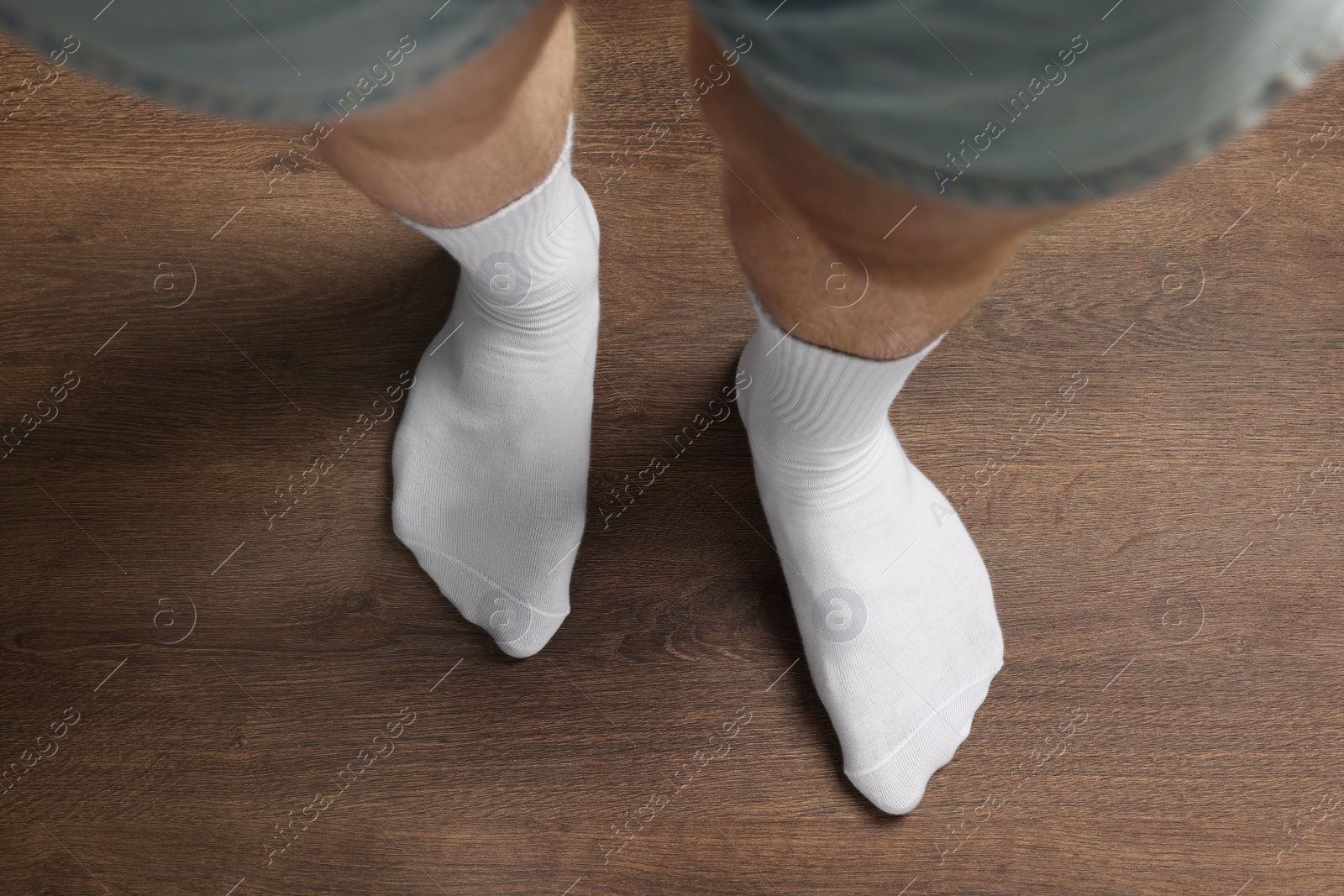 Photo of Man in stylish white socks standing on wooden floor, top view