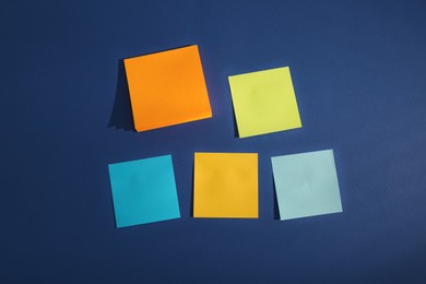 Colorful sticky notes on blue background, flat lay