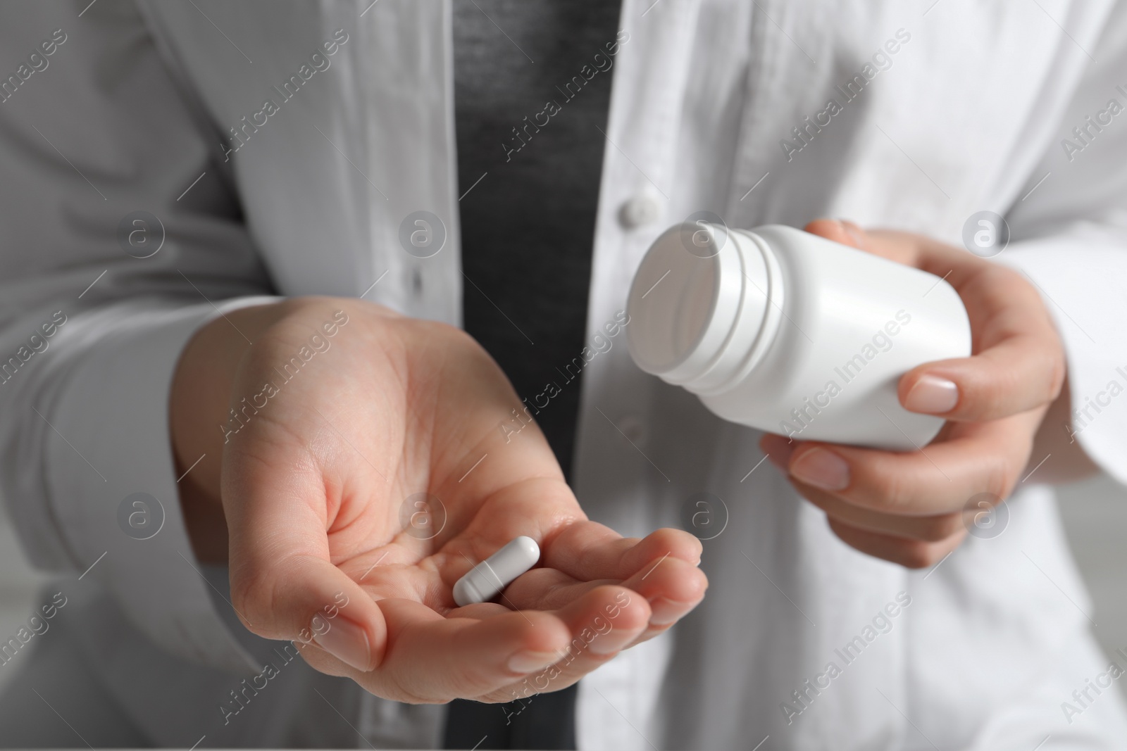 Photo of Woman holding pill and bottle, closeup view