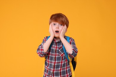 Photo of Portrait of emotional schoolboy on orange background