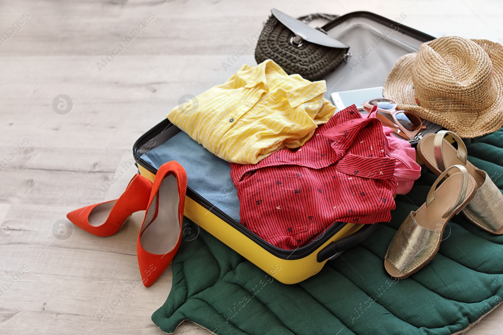 Photo of Open suitcase with clothes and accessories on floor