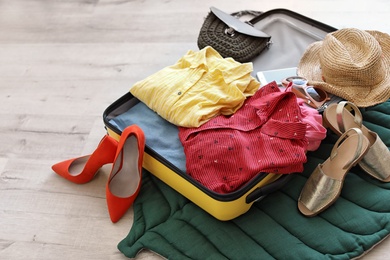 Photo of Open suitcase with clothes and accessories on floor