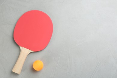 Photo of Ping pong racket and ball on grey table, flat lay. Space for text