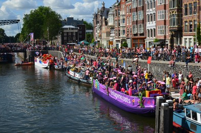 Photo of AMSTERDAM, NETHERLANDS - AUGUST 06, 2022: Many people in boats at LGBT pride parade on river