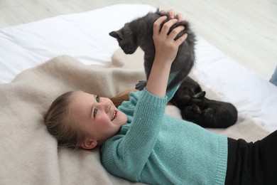 Photo of Little girl with cute fluffy kittens on bed indoors