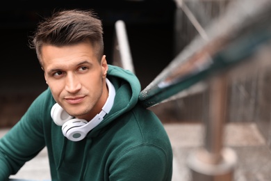 Portrait of handsome young man with headphones outdoors. Space for text