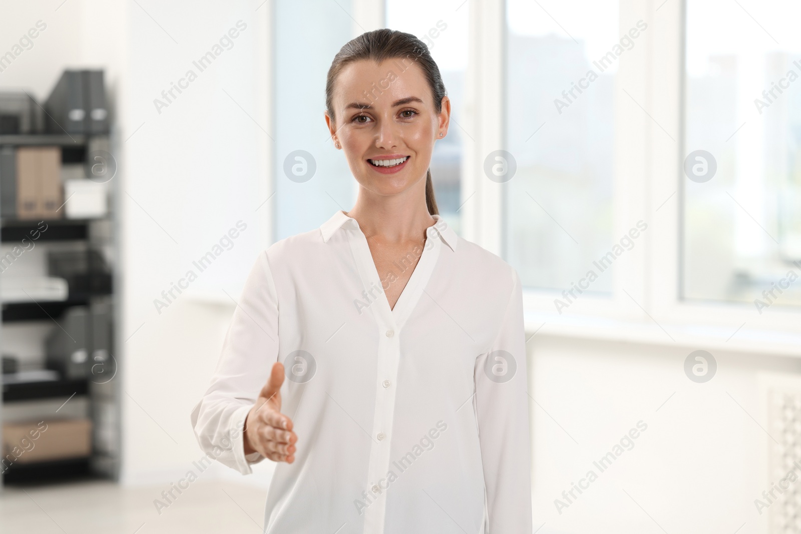 Photo of Happy woman welcoming and offering handshake in office