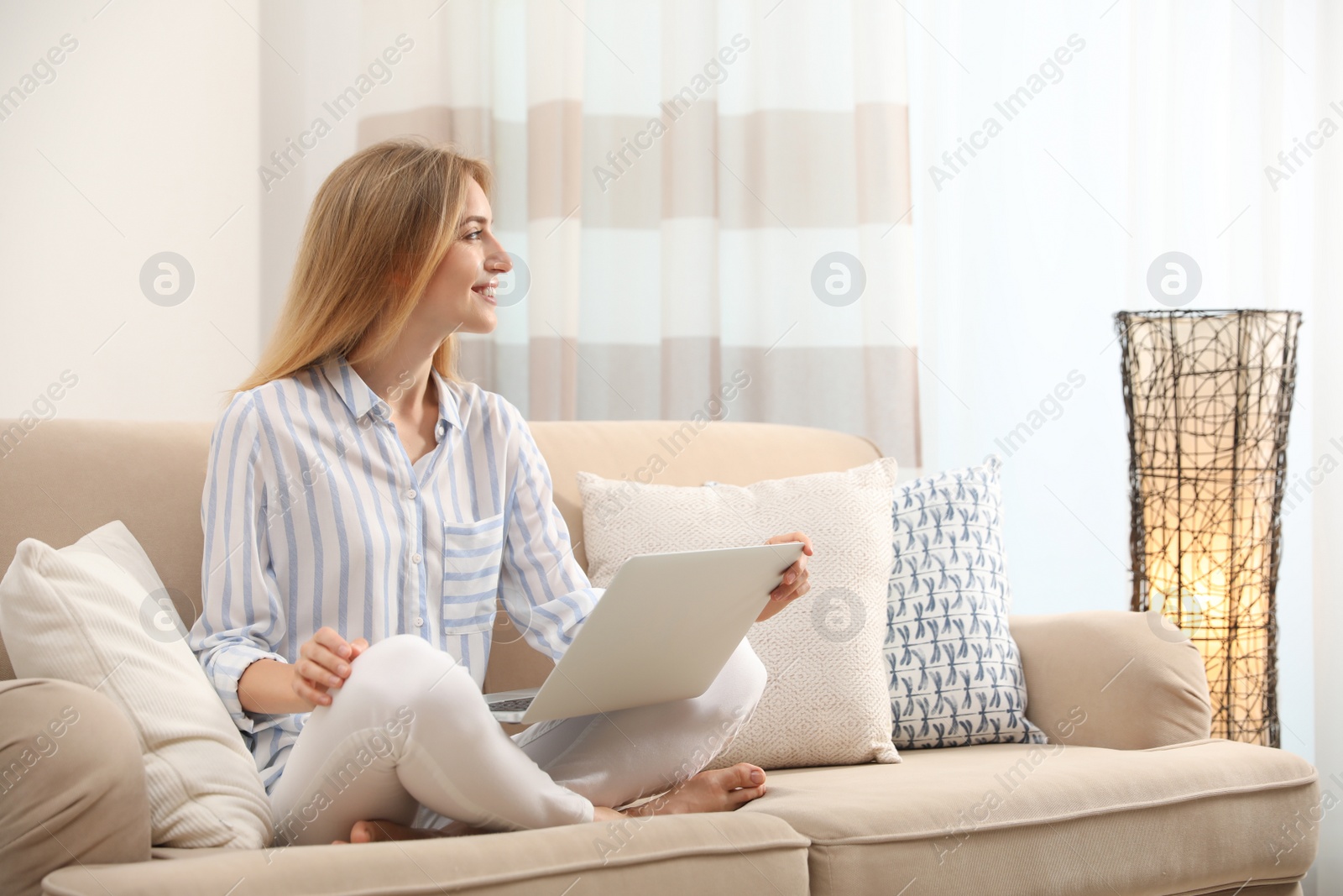 Photo of Pretty young woman with laptop sitting on sofa at home