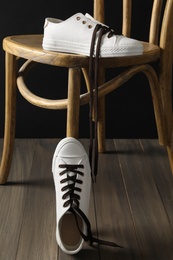 Pair of stylish shoes with brown laces and chair indoors