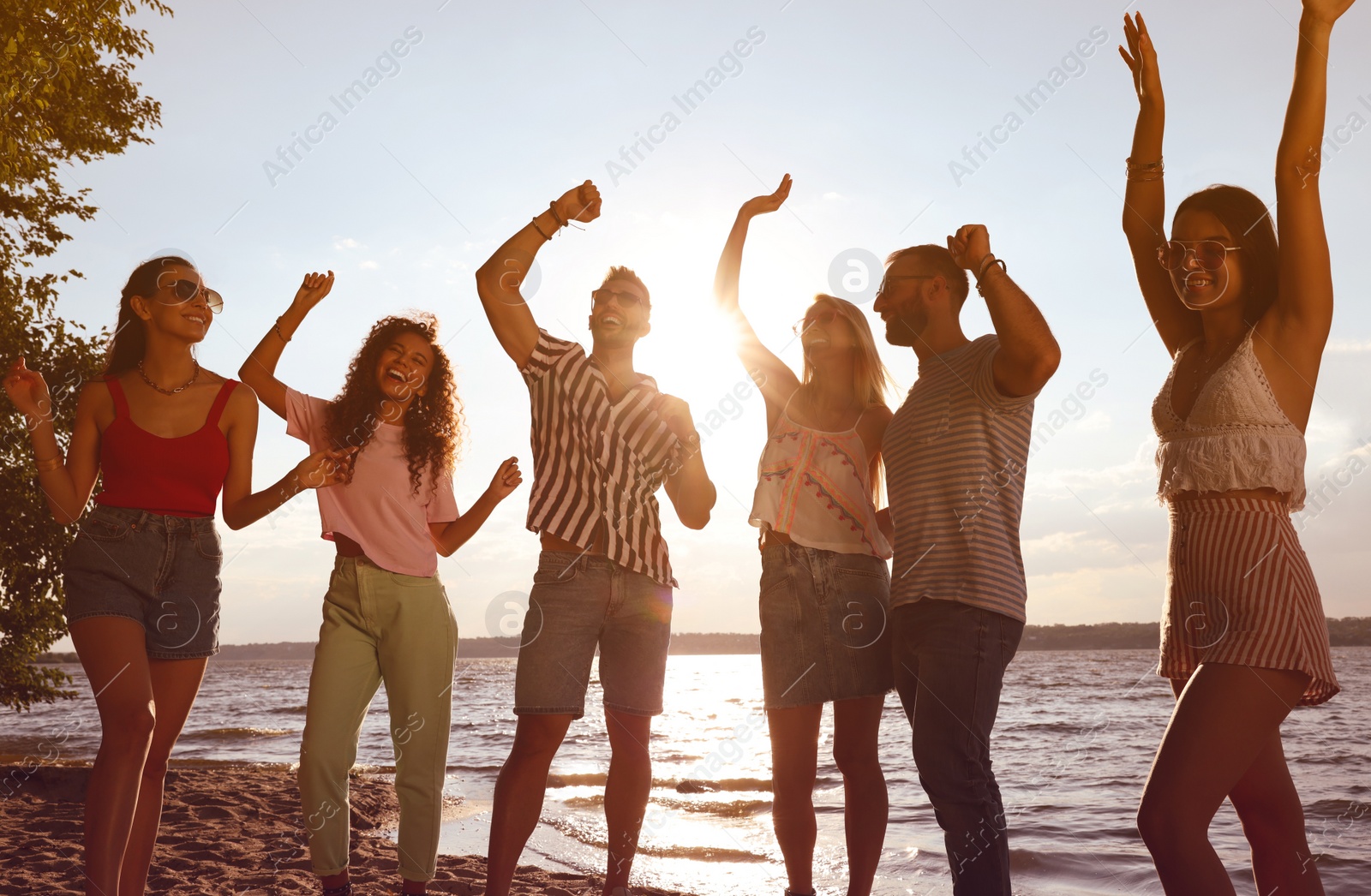 Photo of Group of friends having fun near river at summer party