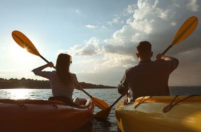 Photo of Beautiful couple kayaking on river, back view. Summer activity