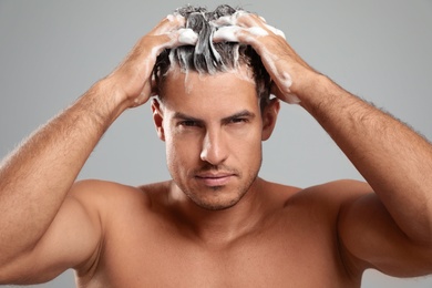 Photo of Handsome man washing hair on grey background