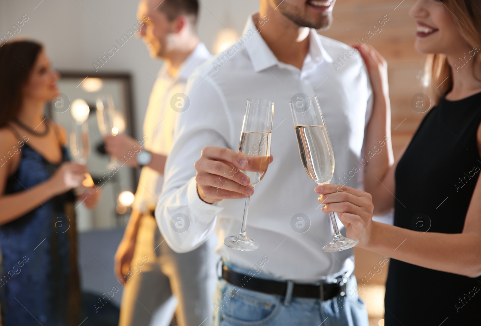 Photo of Couple clinking glasses with champagne at party indoors, closeup