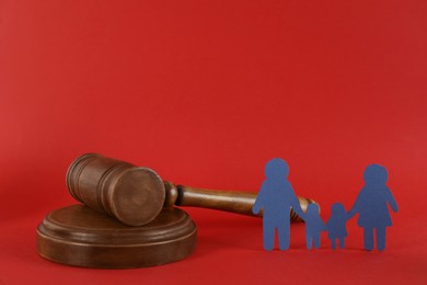 Paper family figure and wooden gavel on red background. Child adoption concept