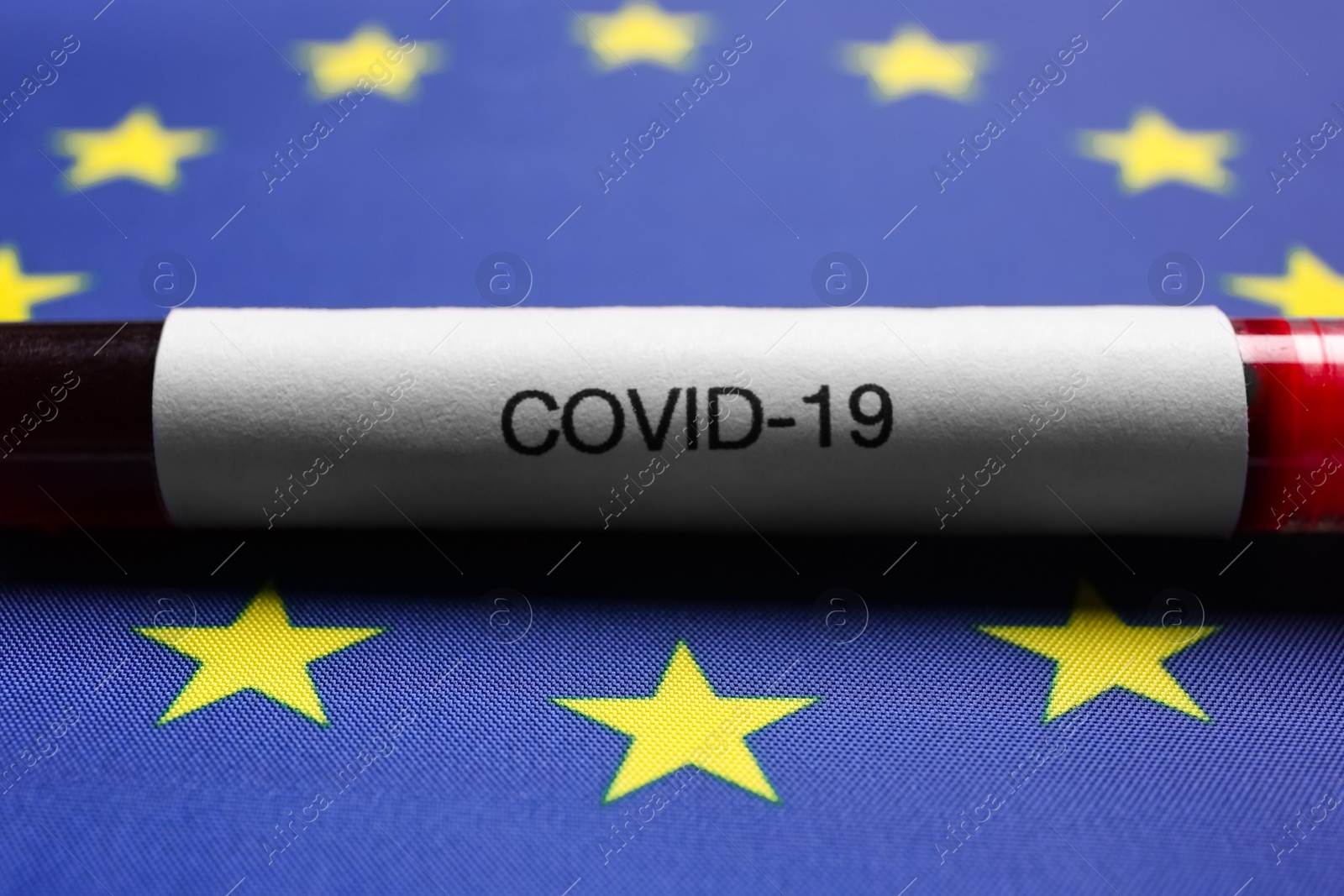 Photo of Test tube with blood sample on European Union flag background, closeup. Coronavirus outbreak