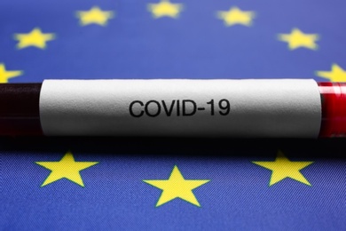 Photo of Test tube with blood sample on European Union flag background, closeup. Coronavirus outbreak