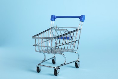 Photo of Small metal shopping cart on light blue background