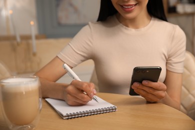 Photo of Woman with smartphone working at cafe in morning, closeup