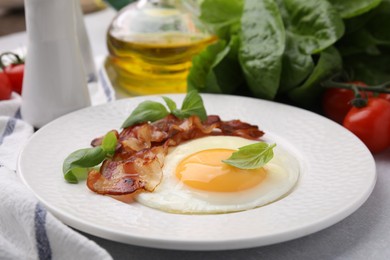 Fried egg, bacon and basil on light grey table, closeup