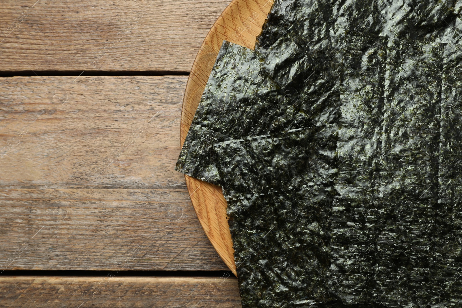 Photo of Plate with dry nori sheets on wooden table, top view. Space for text