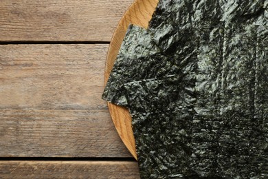 Photo of Plate with dry nori sheets on wooden table, top view. Space for text
