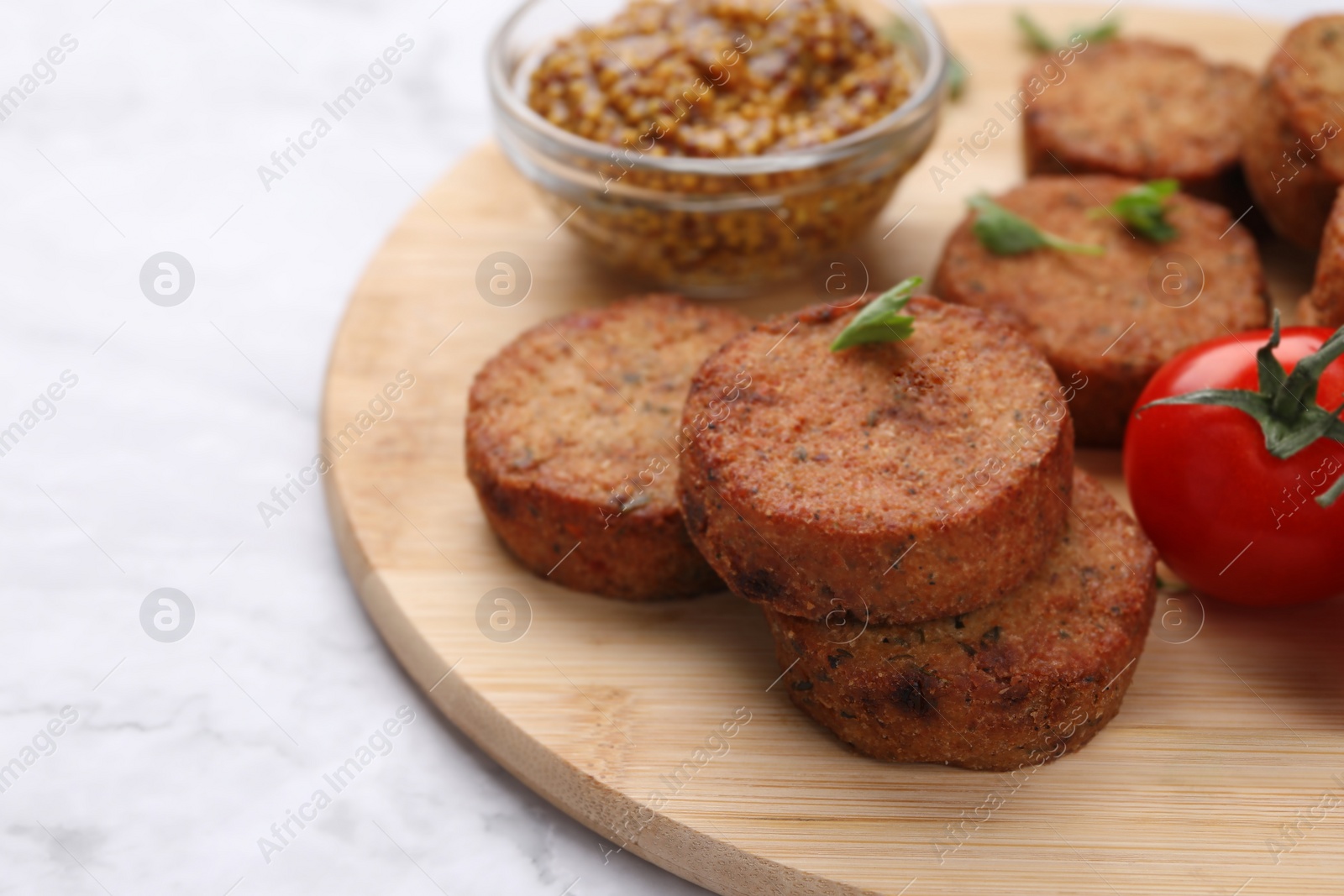 Photo of Tasty vegan cutlets and tomato on white marble table, closeup