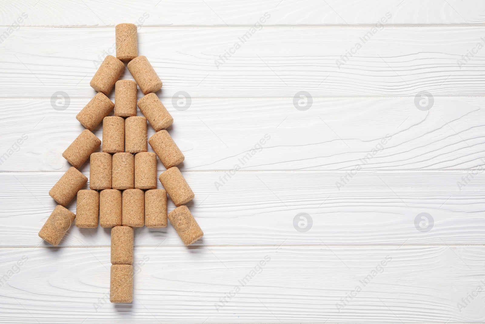 Photo of Christmas tree made of wine corks on white wooden table, top view. Space for text