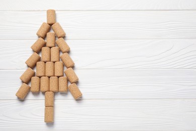 Photo of Christmas tree made of wine corks on white wooden table, top view. Space for text