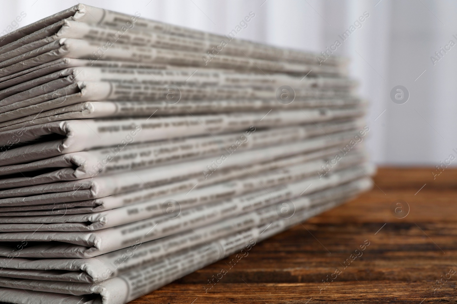 Photo of Stack of newspapers on wooden table, closeup. Journalist's work