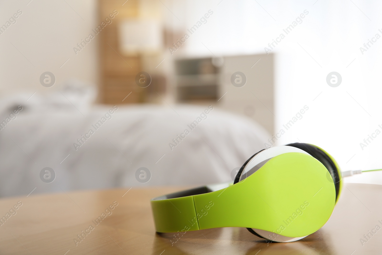 Photo of Stylish modern headphones with earmuffs on table against blurred background, space for text