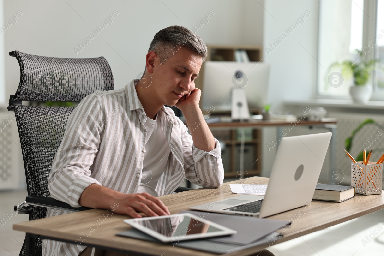 Photo of Man snoozing at wooden table in office