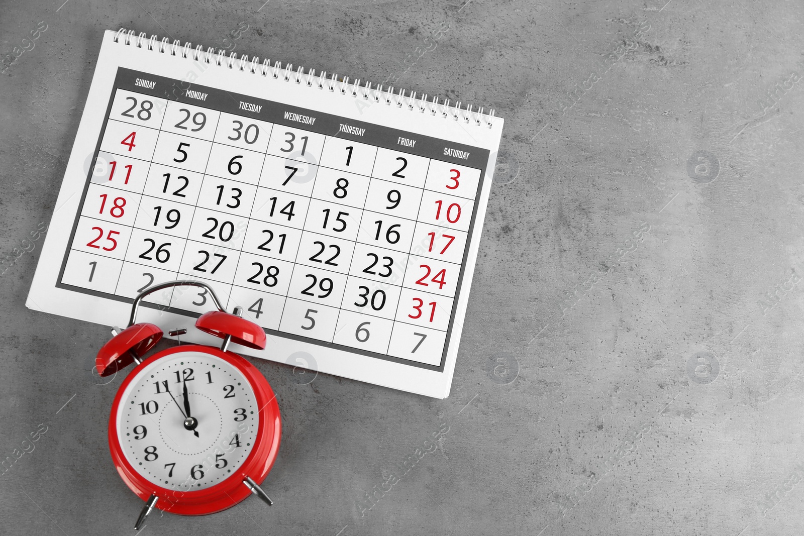 Photo of Calendar and alarm clock on grey stone background, above view