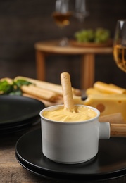 Pot of tasty cheese fondue and products on wooden table