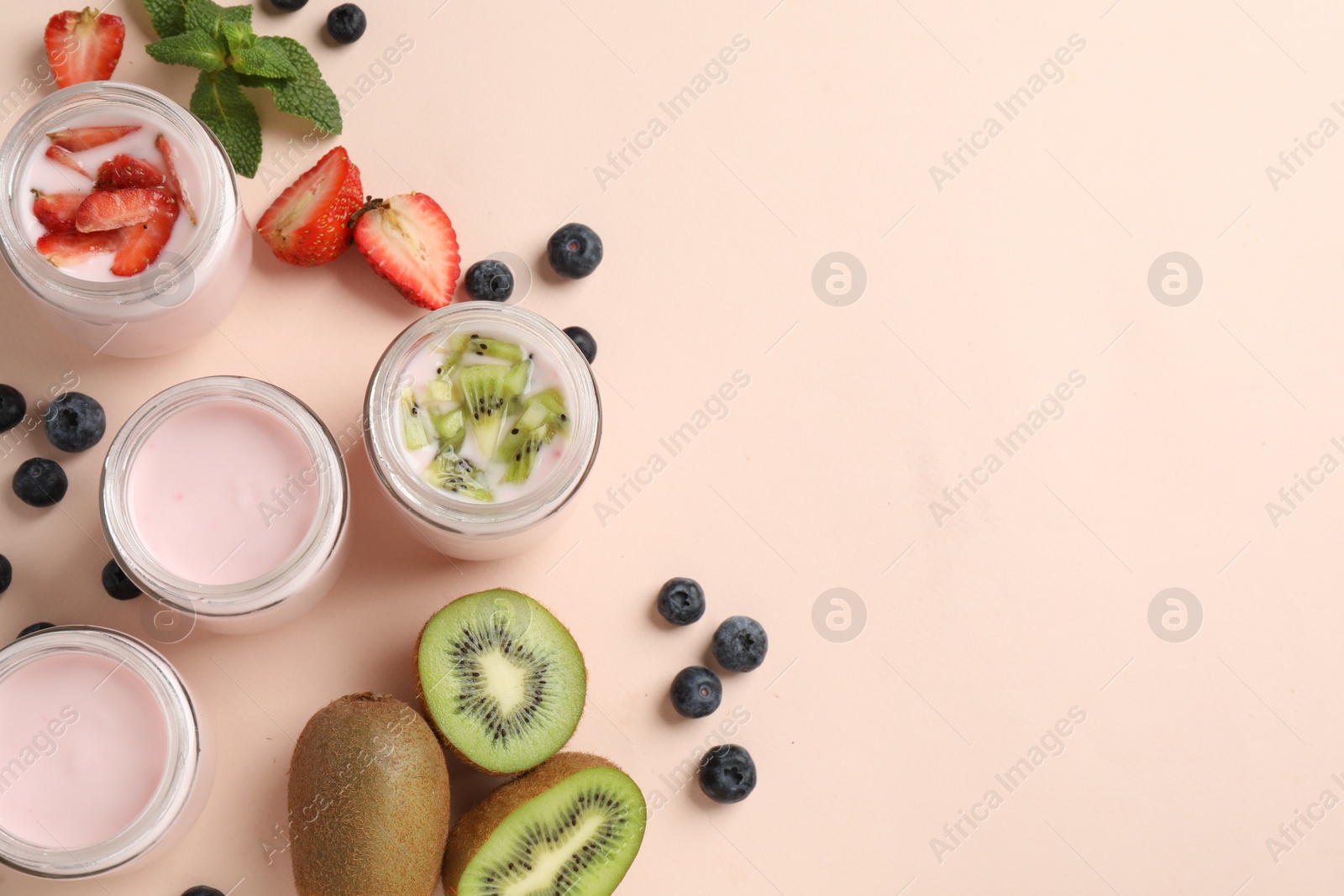 Photo of Jars of fresh yogurt and different fruits on light pink background, flat lay. Space for text