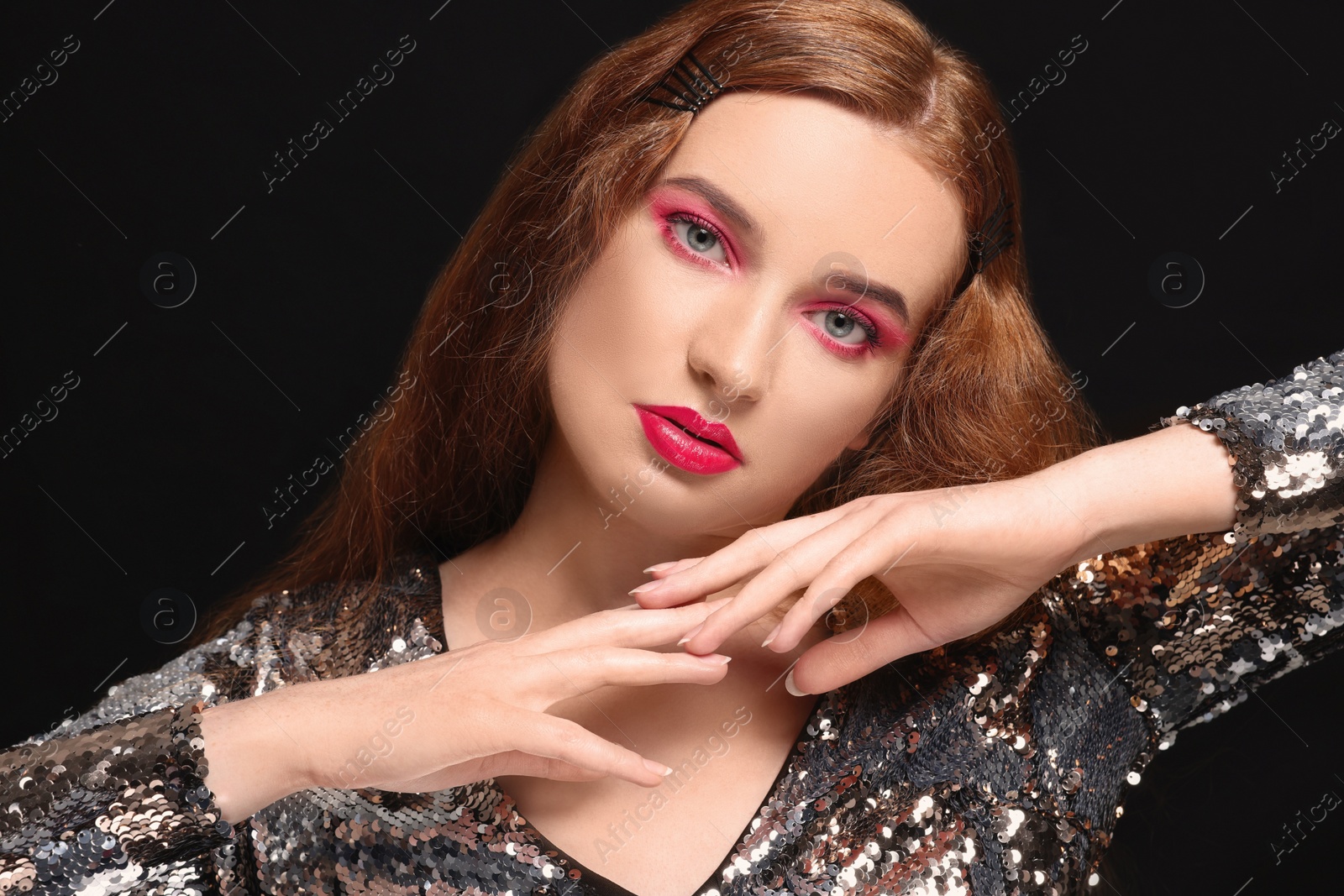 Photo of Portrait of beautiful young woman with makeup posing on black background