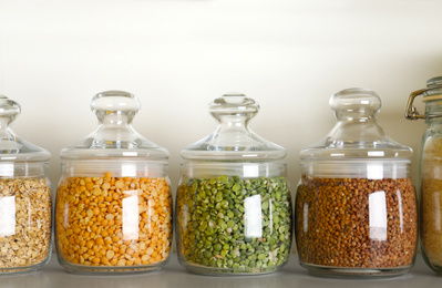 Different types of legumes and cereals in jars on table. Organic grains