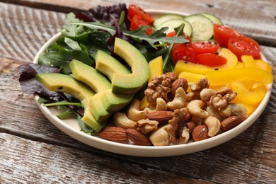 Balanced diet and vegetarian foods. Plate with different delicious products on wooden table, closeup