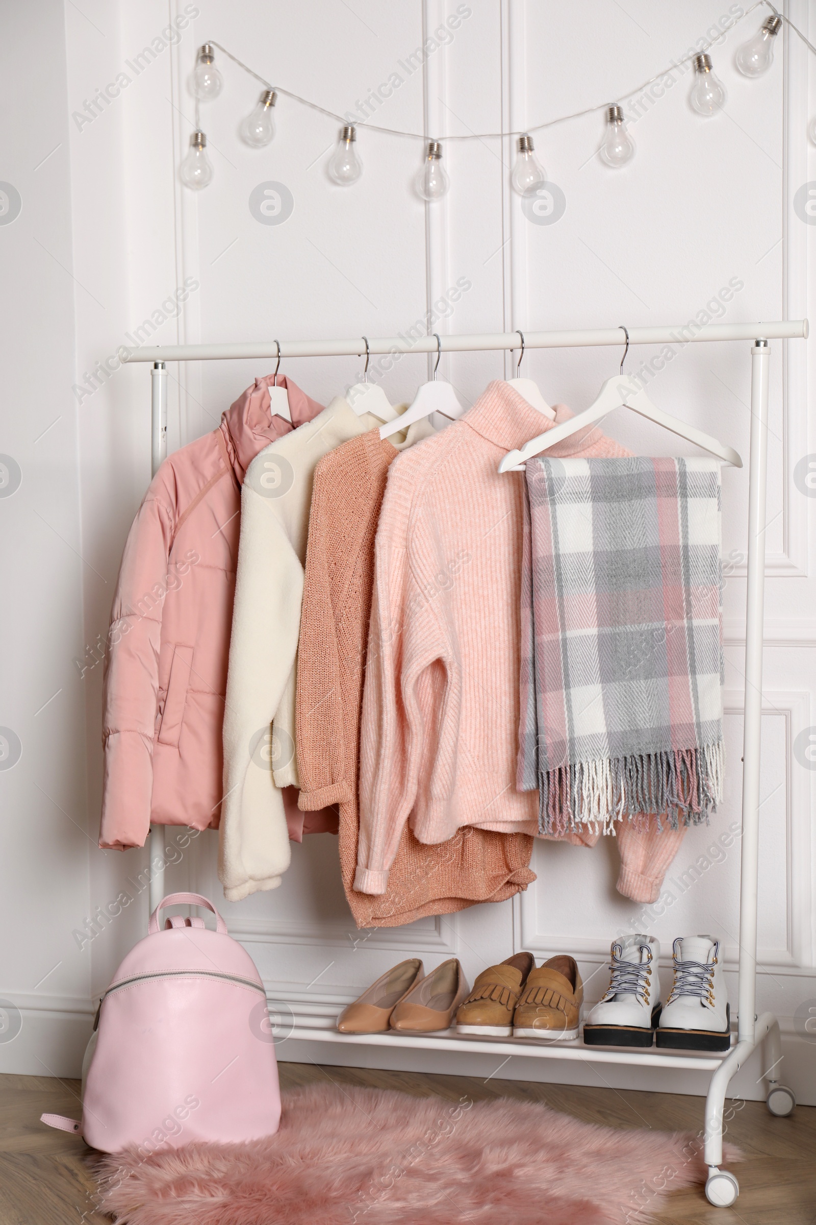 Photo of Rack with stylish warm clothes, shoes and accessories in modern dressing room